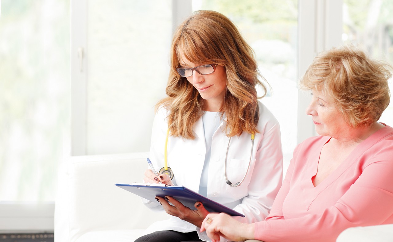 Female doctor consulting with senior patient at private clinic.