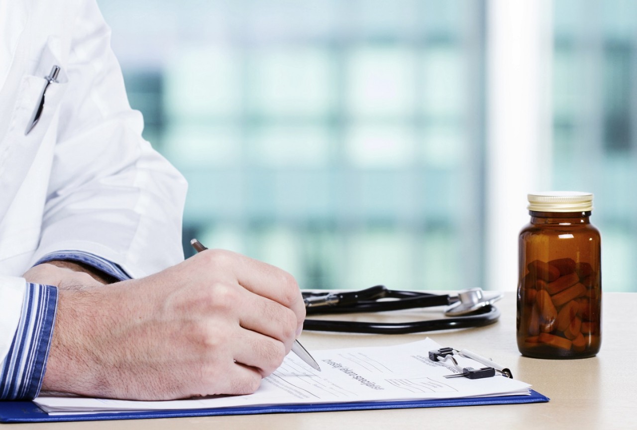 Doctor writing daily report in his office.