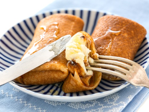 Crepes with cottage cheese and honey on a plate close-up.